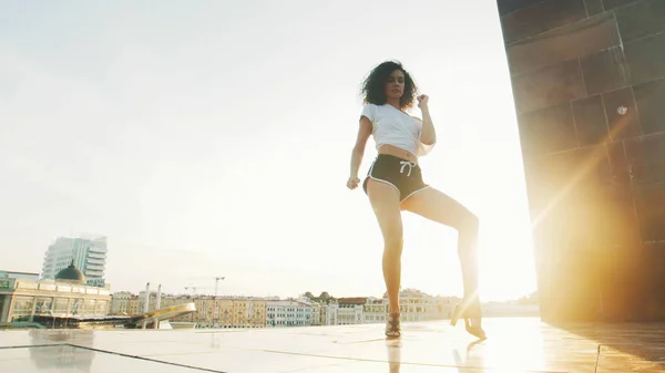 Une jeune danseuse de strip sexy sur des talons hauts montrant des éléments de danse debout sur le fond du coucher de soleil — Photo