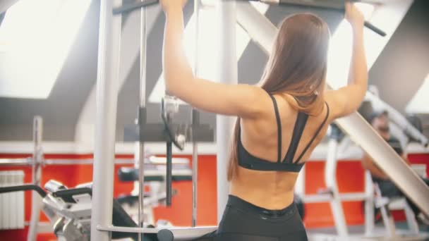 Una atleta entrenando en el gimnasio - sentada y tirando de la barra hacia el cuerpo - Entrenando las manos — Vídeos de Stock