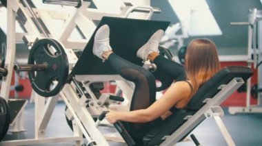 Spor salonunda egzersiz yapan bir atlet kadın - antrenman cihazına bacak presi yapmak