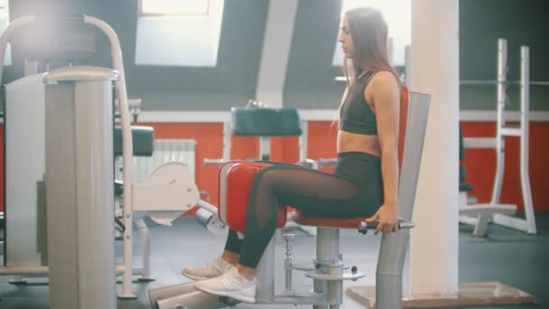 Μια αθλήτρια εκπαίδευση στο γυμναστήριο-τα πόδια που εκτελούν ασκήσεις σε συσκευές εκπαίδευσης πεταλούδα — Αρχείο Βίντεο