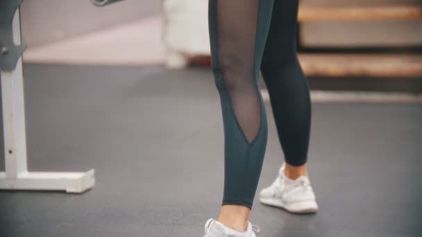 Una mujer en leggins entrenando en el gimnasio, inclinada con una mancuerna de hierro en las manos — Vídeo de stock
