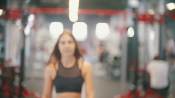 Una atleta caminando en el gimnasio y poniéndose unos auriculares — Vídeo de stock