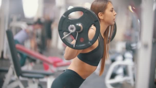 Une athlète s'entraîne dans la salle de gym - accroupi avec haltère sur les épaules — Video