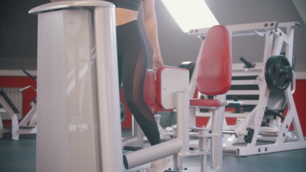 Μια αθλήτρια εκπαιδεύεται στο γυμναστήριο-κάθεται στη συσκευή εκπαίδευσης πεταλούδα και ξεκινά την εκπαίδευση — Αρχείο Βίντεο