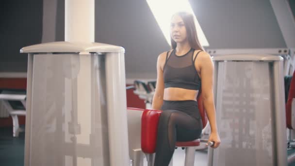 Una atleta con pelo largo entrenando en el gimnasio - ejercitándose en el aparato de entrenamiento de mariposas — Vídeos de Stock