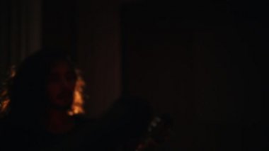 Uzun saçlı genç bir adam sahnede mikrofona yürürken konuşmaya başlar