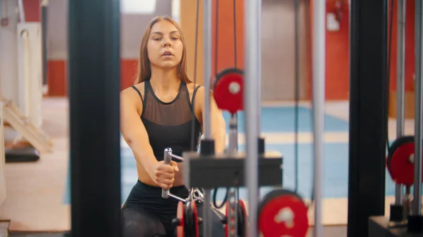 Een atleet vrouw training in de sportschool-het trekken van de handvatten aangesloten op gewicht stukken — Stockfoto