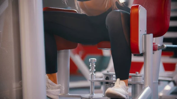 Uma mulher treinando no ginásio - treinando suas pernas no aparelho de treinamento de borboleta — Fotografia de Stock