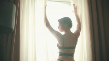 Seksi siyah sütyen ve külot otel odasında pencerenin önünde duran genç kadın