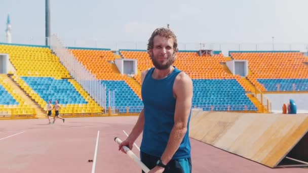 Polsstokhoogspringen-een bebaarde atletische man die een paal vasthoudt en klaar is voor het springen — Stockvideo