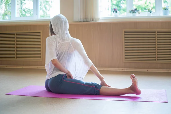 Fiatal karcsú, rugalmas nő ül a szőnyegen, és megy a jóga — Stock Fotó