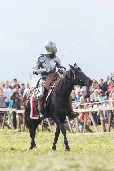 Un caballero con una espada montando un caballo alrededor del campo de batalla - gente mirando detrás de la valla —  Fotos de Stock
