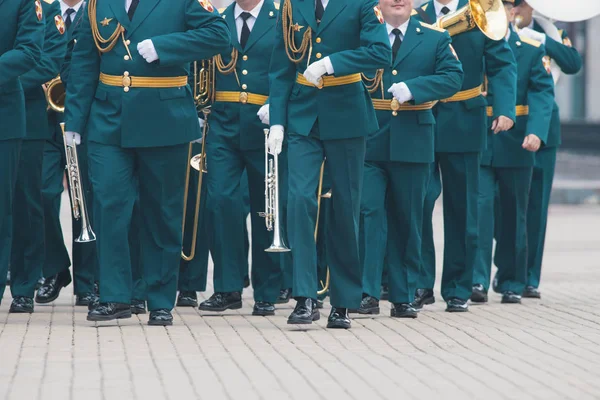 Un desfile de instrumentos de viento - gente con trajes verdes caminando por la calle sosteniendo instrumentos — Foto de Stock