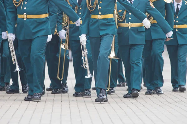 Una sfilata di strumenti a fiato - gente in costume verde che cammina per strada con strumenti musicali — Foto Stock