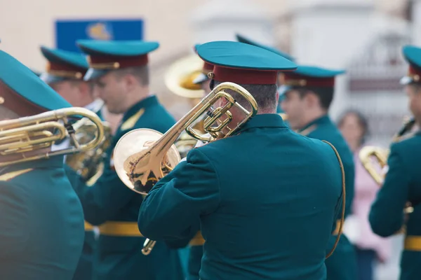 Una sfilata di strumenti a fiato - uomo in costume verde che tiene una tromba e la suona — Foto Stock