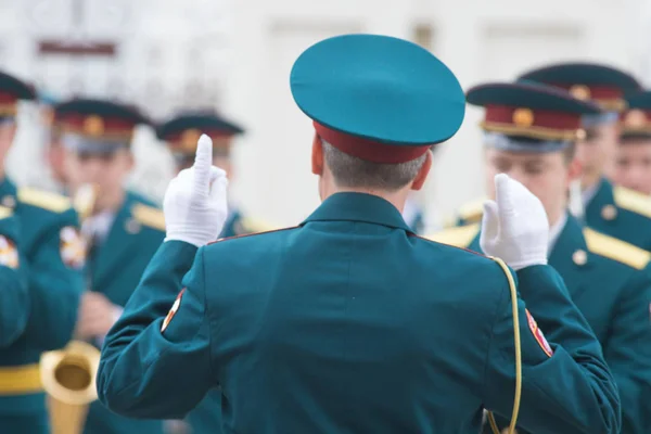 Un desfile de instrumentos de viento - gente con trajes verdes escuchando al conductor —  Fotos de Stock