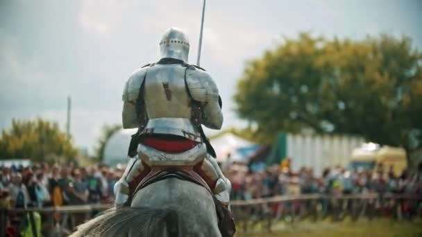 Un caballero montando un caballo alrededor del campo de batalla y la gente mirando detrás de él la cerca el caballo se levanta — Vídeos de Stock