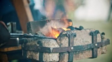 Demirci atölyesinde demir detaylarla çalışıyor - uzun detayları ısıtıp kömürlerden çıkarıyor