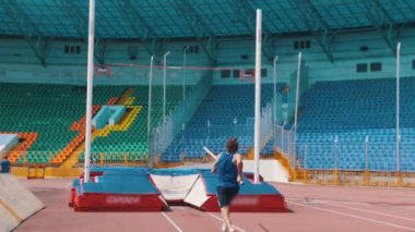 Sırıkla atlama - bar üzerinden atlayan sakallı atletik bir adam