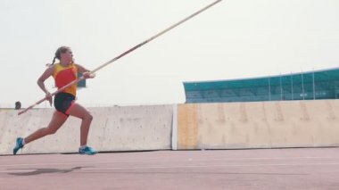 Kazan, Rusya 26-07-2019: Sırıkla atlama - Genç bir atletik kadın barın üzerinden atladı ve meslektaşları onu izliyor