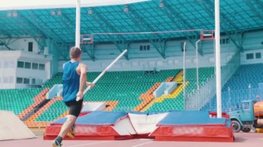 Pole vault eğitim - stadyumda bar üzerinden atlayan bir atletik adam