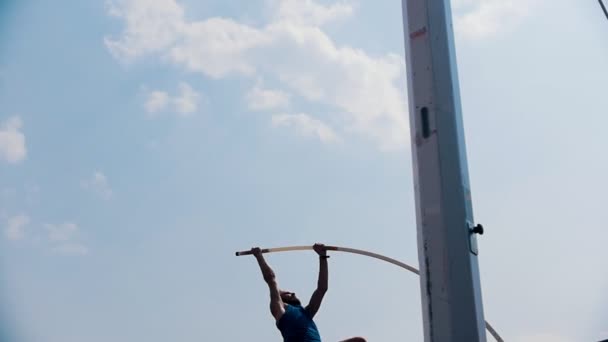 Pole vault training on the stadium outside- an athletic man jumping over the bar and falling down with the bar - unsuccessful attempt — Stock Video