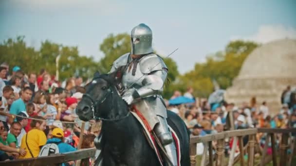 BULGAR, RUSIA 11-08-2019: Un caballero con una espada montando un caballo alrededor del campo de batalla - personas mirando detrás de la valla — Vídeo de stock