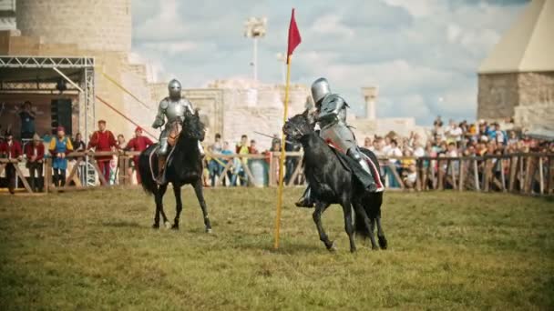 BULGAR, RUSIA 11-08-2019: Caballeros con espadas montando a caballo en el campo de batalla y teniendo una batalla de entrenamiento - personas mirando detrás de la valla — Vídeos de Stock