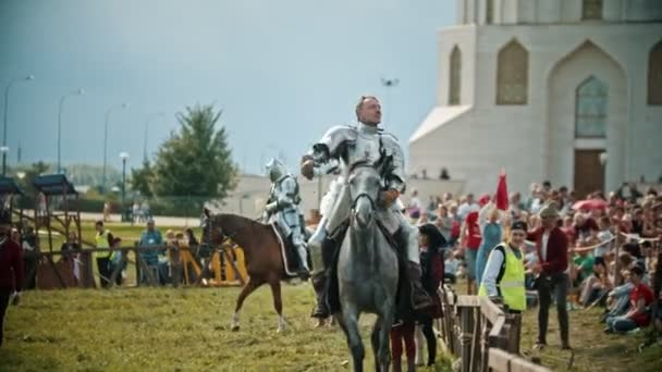 BULGAR, RÚSSIA 11-08-2019: Um cavaleiro montando um cavalo ao redor do campo de batalha e cumprimentando as pessoas que observam por trás da cerca — Vídeo de Stock