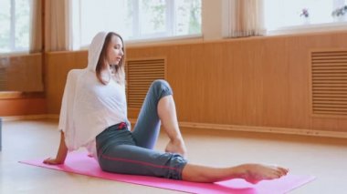 Genç kadın jimnastikçi stüdyoda yerde oturan ısınma