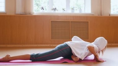 Genç kadın jimnastikçi stüdyoda katta oturan ısınma - yere bükme - germe