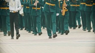Bir rüzgarlı enstrüman geçit töreni - yeşil kostümleri askeri müzisyenler müzik aletleri tutarak sokakta yürüyüş