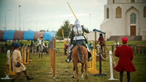BULGAR, RUSSIA 11-08-2019: Knights having a battle on the field - running on each other and breaking the plastic spear - assistens watching them — Stock Video