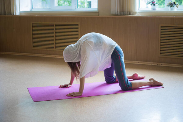 Молодая довольно женщина тренируя на циновке yoga - выполняя тренировку для поясницы и позвоночника - изгиб ее назад вверх
