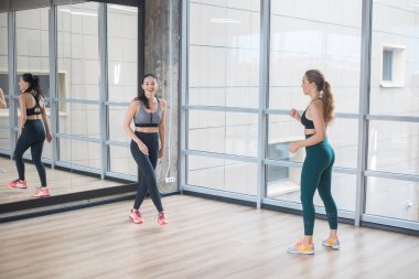 Büyük aynalar ile parlak fitness stüdyosunda duran iki genç kadın