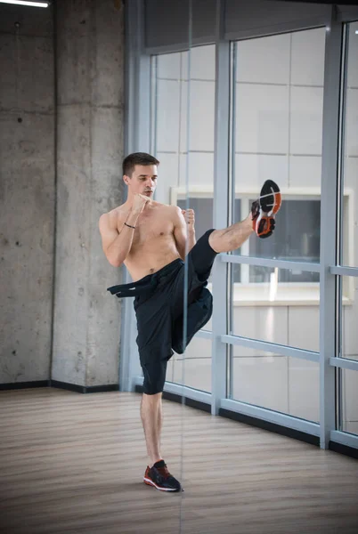 Un uomo atletico in piedi in posa combattimento in studio - mostrando il calcio — Foto Stock