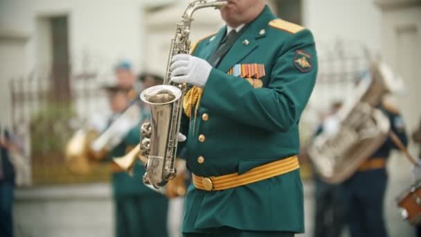 Um desfile militar de instrumentos de sopro - um homem de traje verde tocando saxofone — Vídeo de Stock