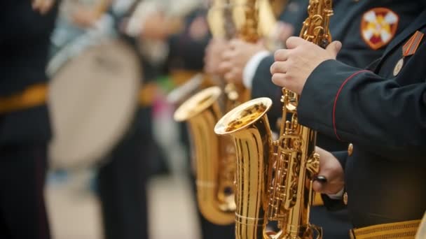 Een blaasinstrument Parade-mannen in donkere kostuums spelen saxofoon Outdoors-militaire muziekfestival — Stockvideo