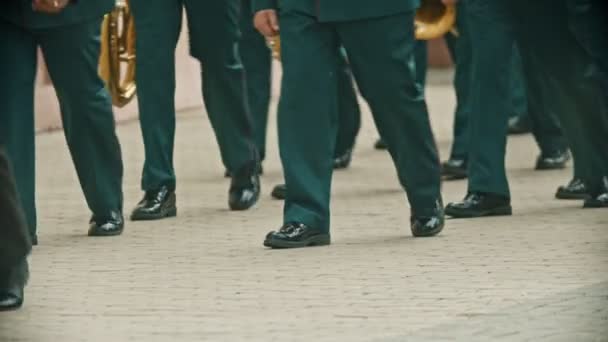 Um desfile de instrumentos de sopro - pessoas em trajes verdes andando na rua segurando instrumentos musicais - festival musical militar — Vídeo de Stock