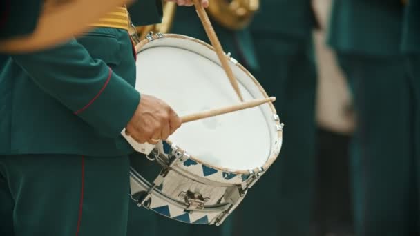 Военный парад духовых инструментов - человек в зеленом костюме, играющий на барабанах на улице — стоковое видео