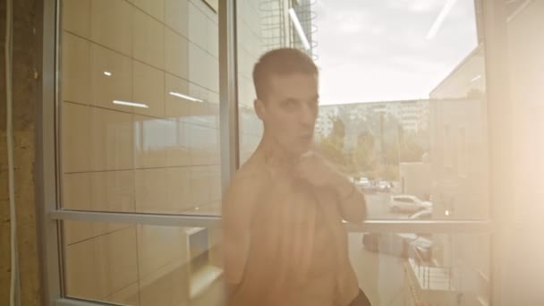 Un boxeador atlético de pie junto a la ventana y el boxeo a la cámara — Vídeo de stock