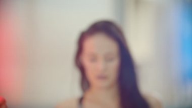 Bir kadın kameraya yakın gelir ve at kuyruğu saçlarını koyarak - neon aydınlatma