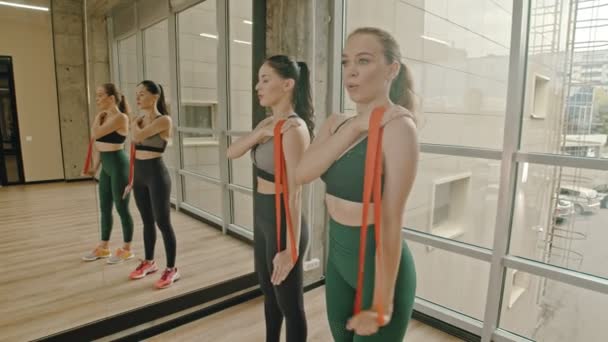 Duas mulheres saudáveis de pé no estúdio e treinando sua mão com uma alça de alongamento — Vídeo de Stock