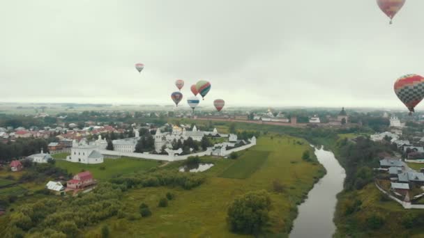 18-07-2019 Suzdal, Russia: different huge colorful air balloons are flying over the village - different inscriptions of brands on the balloons — Stock Video