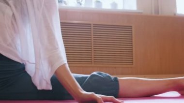 Genç kadın yoga mat üzerinde oturan bir bölünmüş performans - germe egzersizleri yapıyor - yanlara bükme - dans stüdyosu
