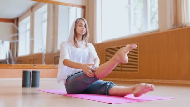 Jonge vrouw gymnast warming-up zittend op de vloer in de Studio-been stretching — Stockvideo