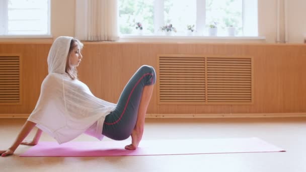 Jovem bailarina mulher em capuz branco fica em seus dedos da ponta no tapete de ioga - estúdio de dança . — Vídeo de Stock