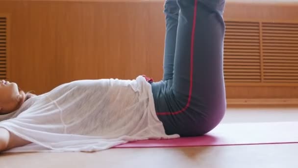 Jovem mulher magra com cabelo loiro deitado no chão com as pernas para cima e exercendo — Vídeo de Stock