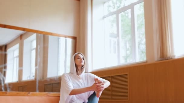 Jeune femme mince échauffement assis sur le tapis de yoga saisir le pied et faire des exercices de jambes — Video