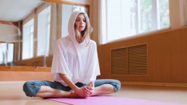 Genç ince kadın lotus pozisyonda yoga mat üzerinde oturan ve ısınma